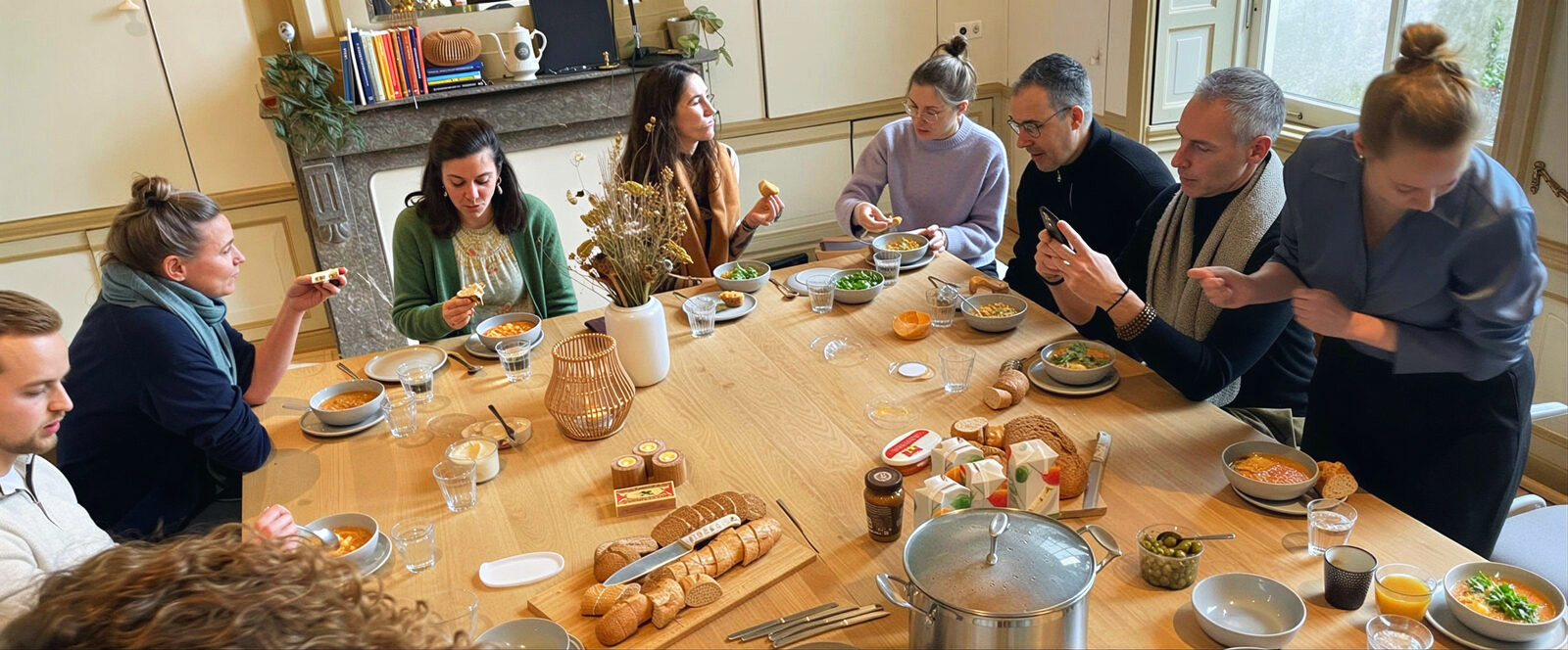 Participants sharing soup and bread around a long wooden table during a training day